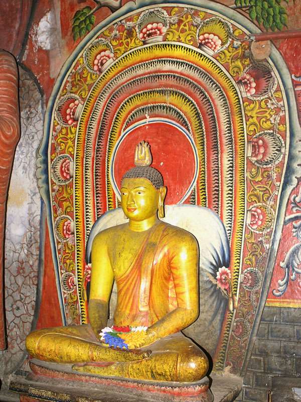 Eine der weit über 100 Buddha-Statuen der Höhlentempel vor einer typischen Wandmalerei; Foto: 09.11.2006, Dambulla