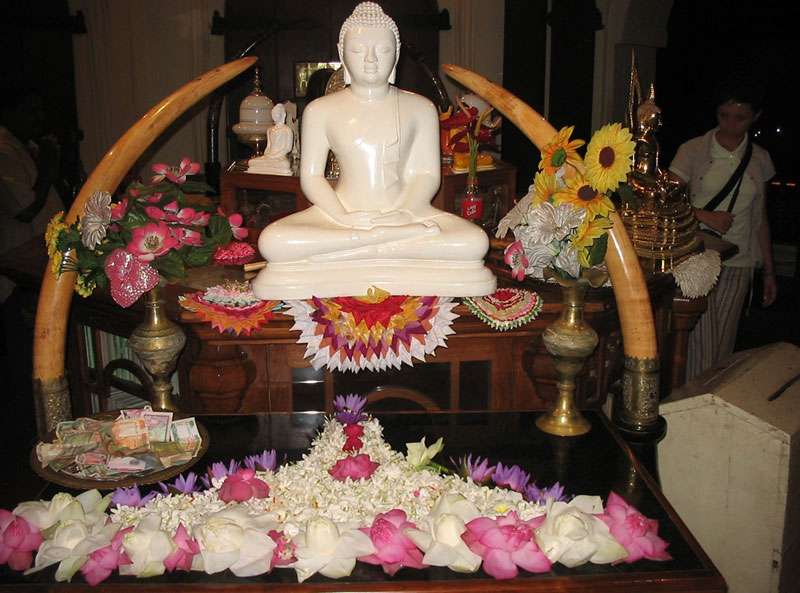 Eine der unzähligen Buddha-Statuen im Zahntempel ist von Opfergaben umgeben; Foto: 10.11.2006, Kandy
